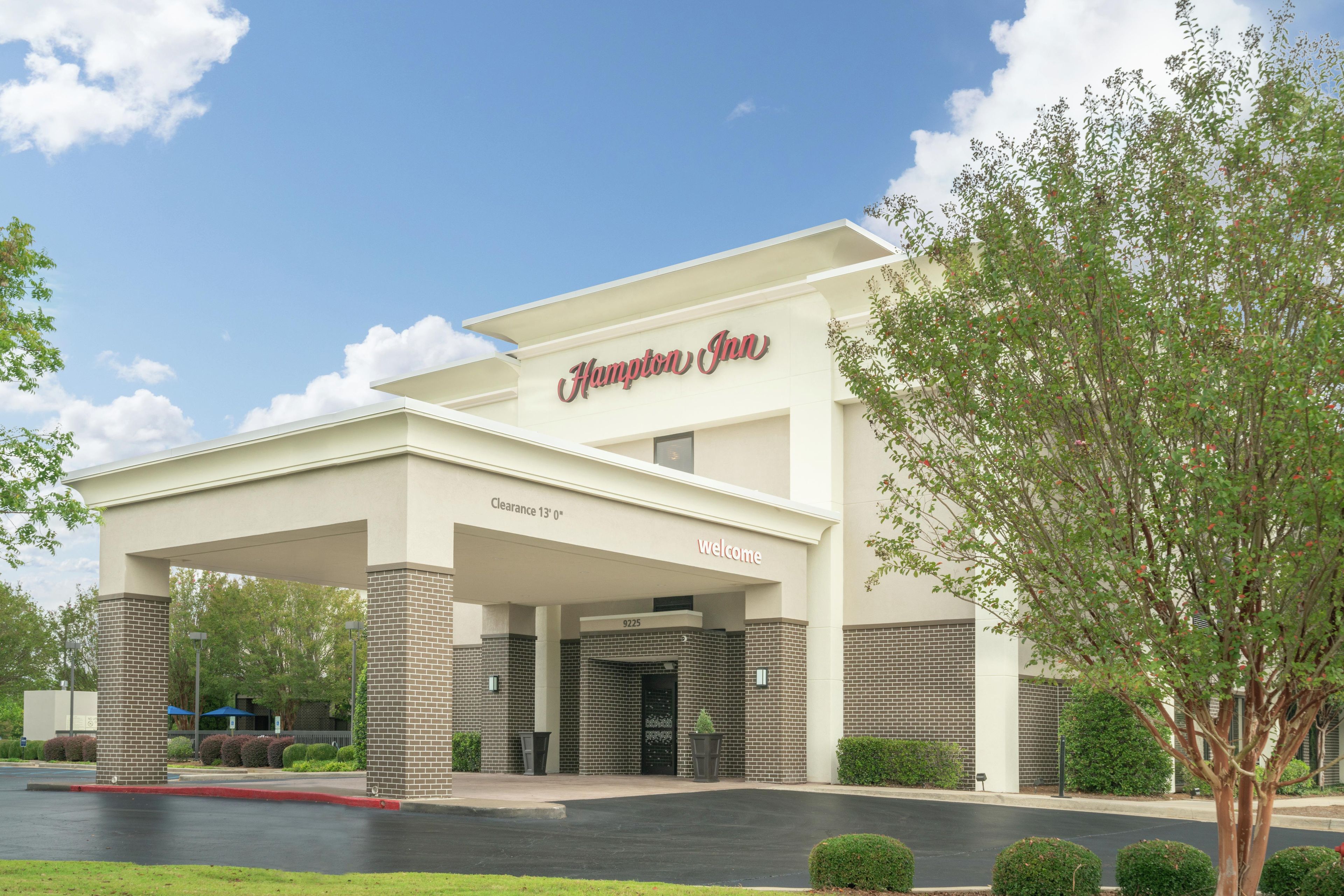 A Hampton Inn hotel with a clear entrance, a sign indicating a clearance of 13 feet, and a welcoming sign.