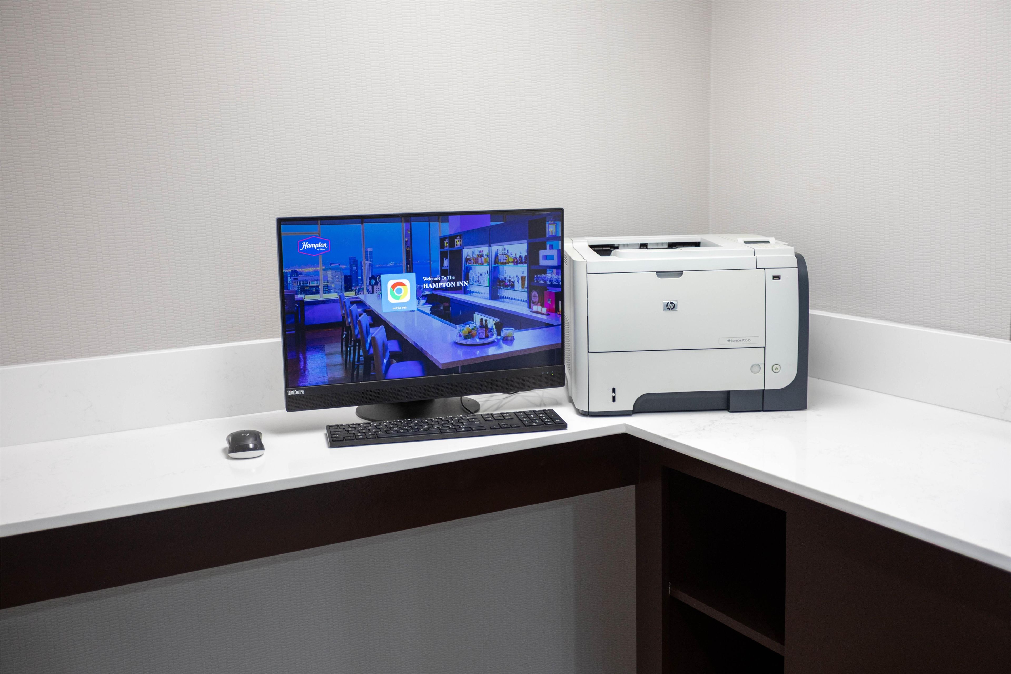 Un monitor de computadora mostrando un sitio web de hotel, un teclado y una impresora sobre un escritorio.