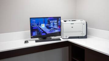 Un monitor de computadora mostrando un sitio web de hotel, un teclado y una impresora sobre un escritorio.