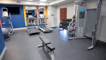 A gym with treadmills, a bench, dumbbells, and a weight machine.