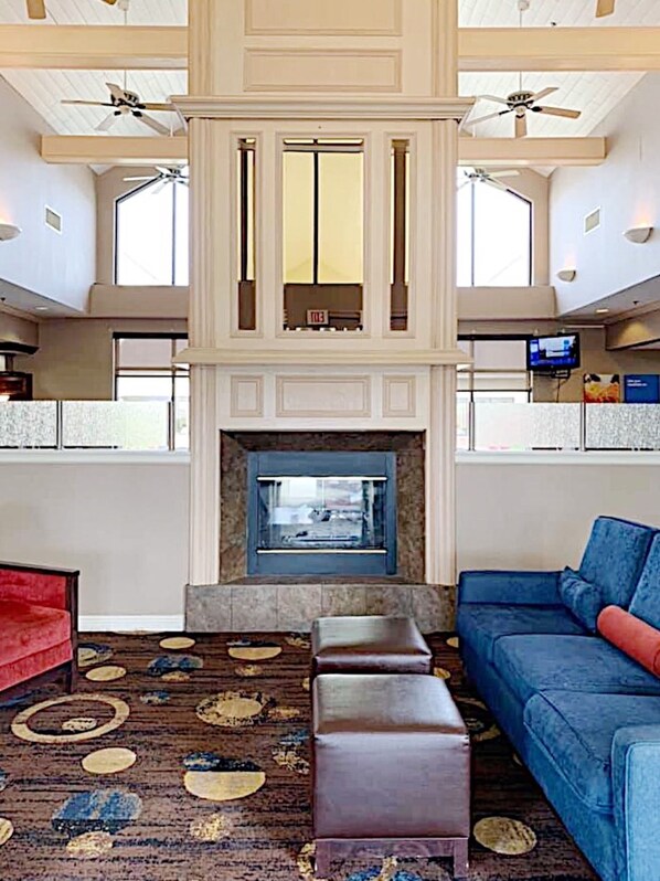 A spacious lobby with a high ceiling, a fireplace, and a large blue sofa.
