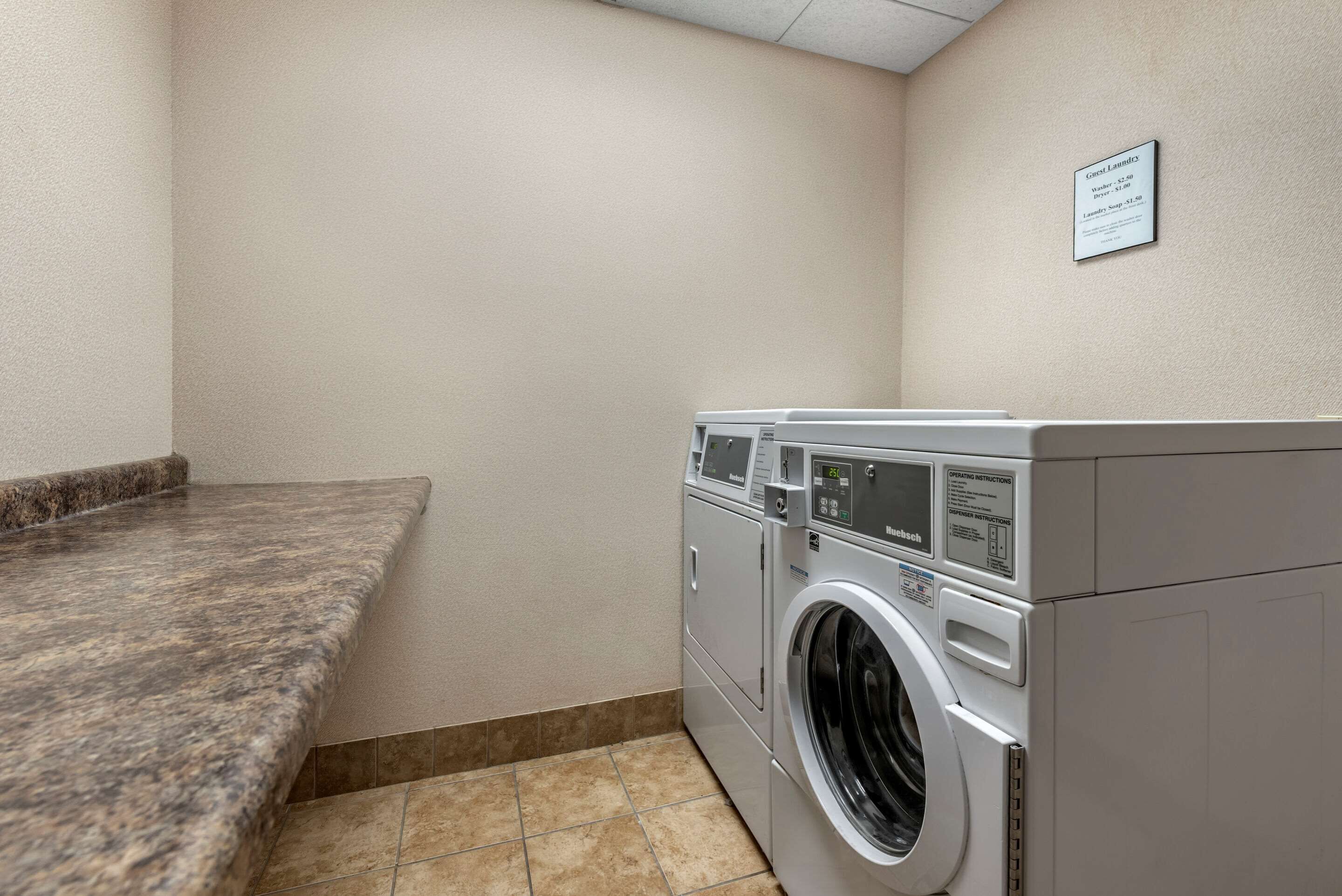 A laundry room with a granite countertop and two stacked washers and dryers.