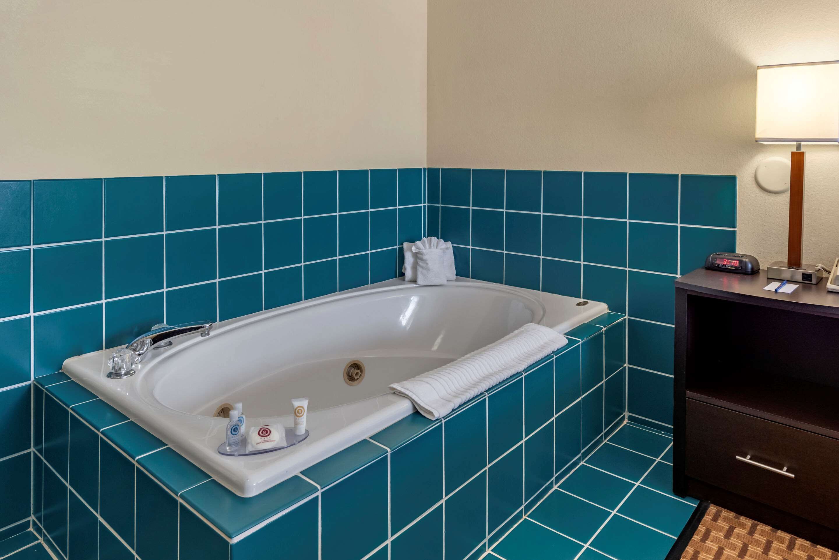 A bathroom with a bathtub, a towel, and toiletries.