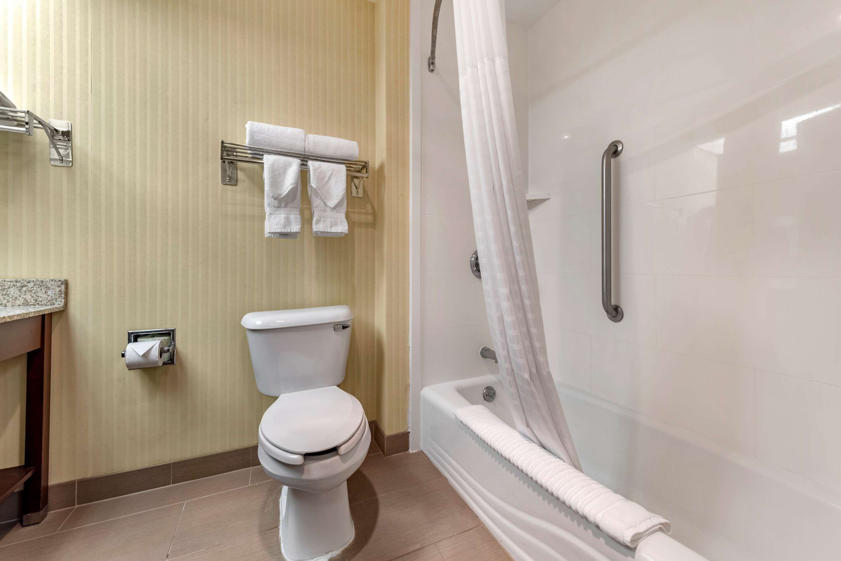 A bathroom with a toilet, a shower with a glass door, and a towel rack with towels.