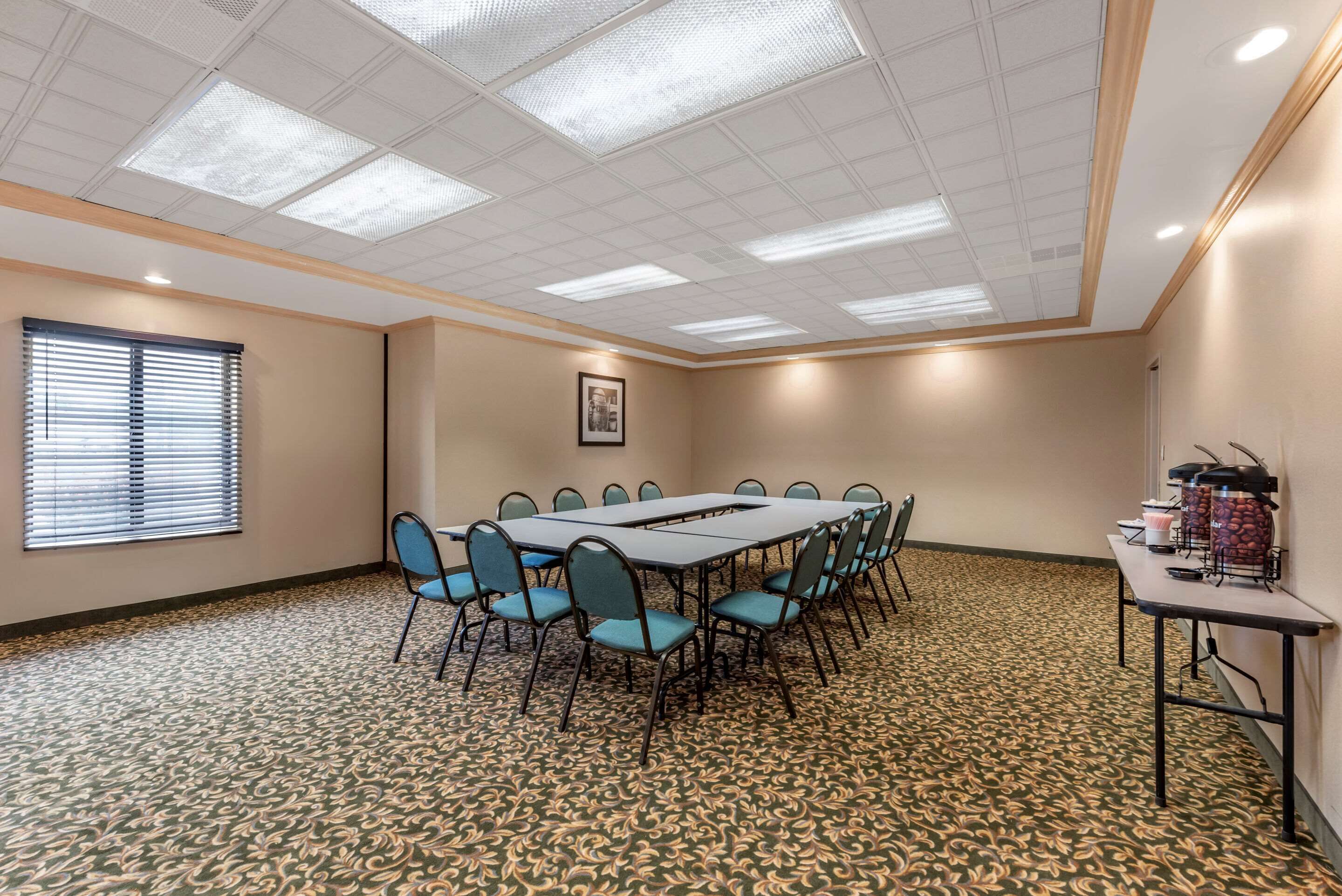 A conference room with a long table and chairs, a patterned carpet, and a ceiling with recessed lighting.