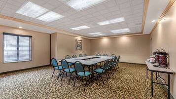 Une salle de conférence avec une longue table et des chaises, un tapis à motifs et un plafond doté d’un éclairage encastré.