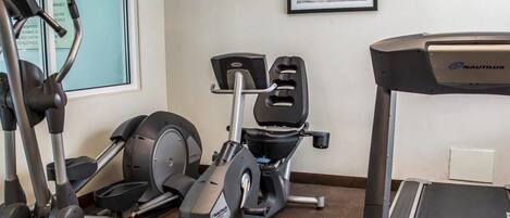 Un gimnasio con bicicletas estáticas, una máquina elíptica y una cinta de correr.