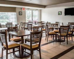 Un comedor con varias mesas y sillas, un letrero de salida y un televisor montado en la pared.