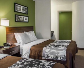 A hotel room with a bed, bedside table, lamp, and two framed pictures on the wall. - Sleep Inn Historic Williamsburg (Williamsburg)
