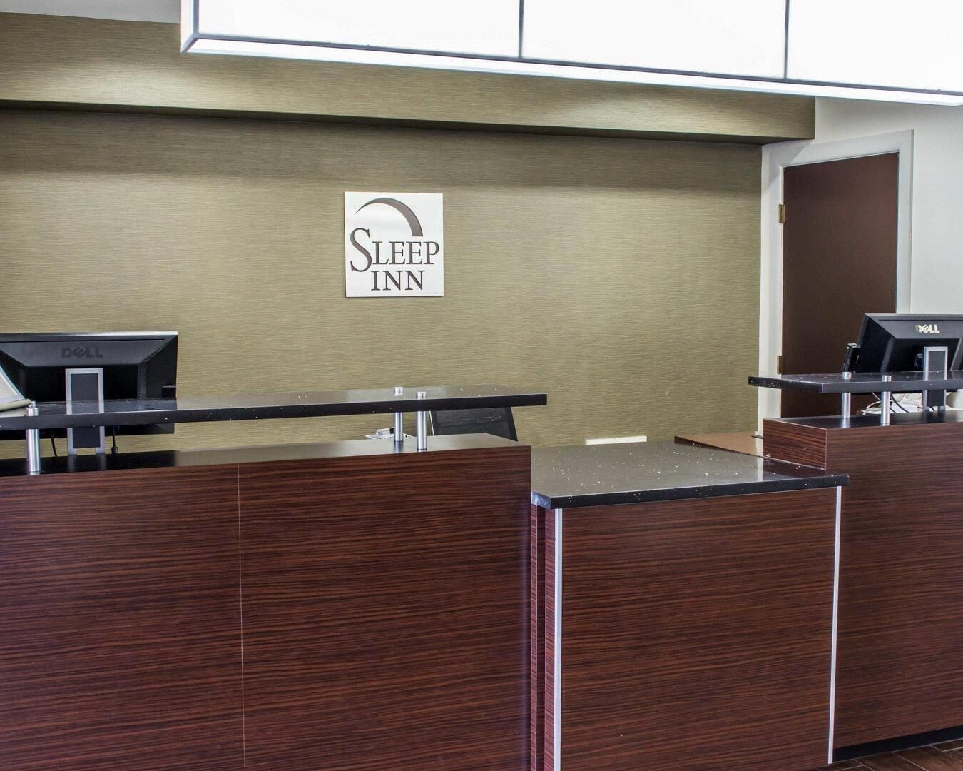 A reception desk with a sign that reads 'Sleep Inn' and two computer monitors.