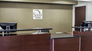 A reception desk with a sign that reads 'Sleep Inn' and two computer monitors. - Sleep Inn Historic Williamsburg (Williamsburg)