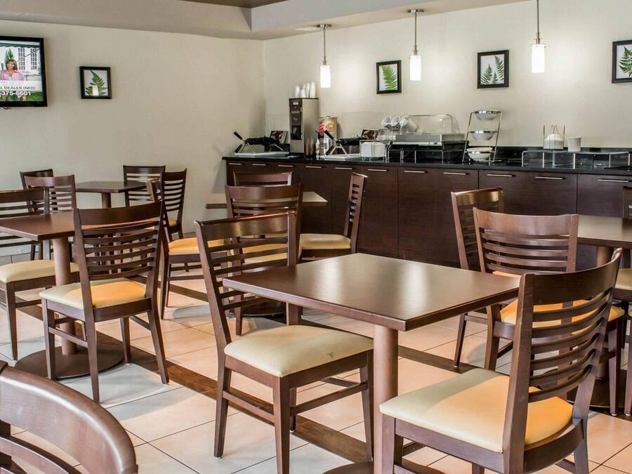 Ein Restaurant mit Holztischen und -stühlen, einer Küche und gerahmten Bildern an den Wänden.