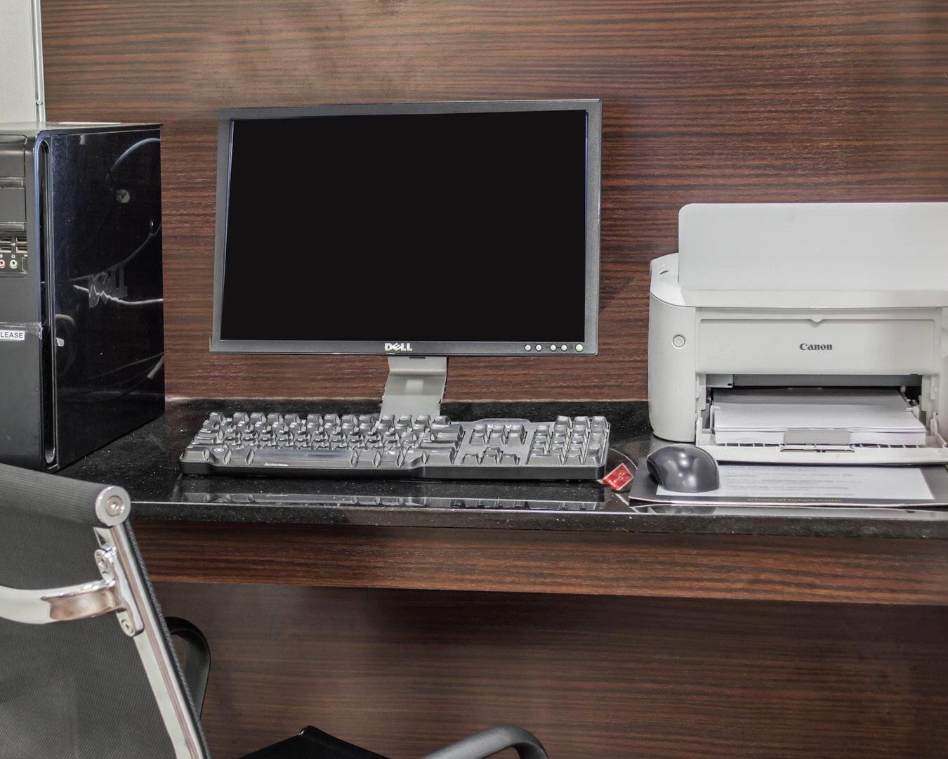 A desk with a Dell monitor, a Canon printer, and a keyboard.
