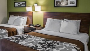 A hotel room with two beds, a nightstand, a lamp, and framed pictures on the wall. - Sleep Inn Historic Williamsburg (Williamsburg)
