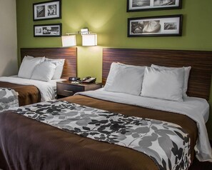 A hotel room with two beds, a nightstand, a lamp, and framed pictures on the wall. - Sleep Inn Historic Williamsburg (Williamsburg)