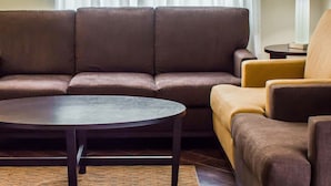 A modern living room with a brown sofa set, a round coffee table, and a yellow armchair. - Sleep Inn Historic Williamsburg (Williamsburg)