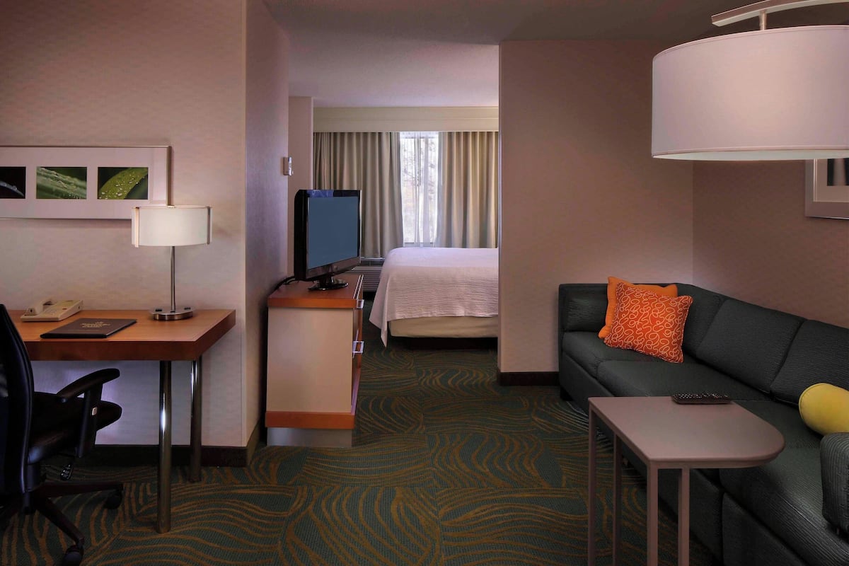 Une chambre d’hôtel équipée d’un bureau, d’une chaise, d’un lit, d’un canapé et d’une petite table.