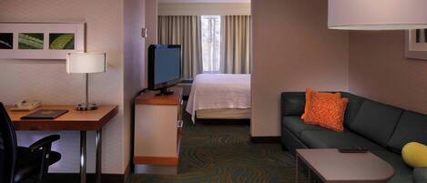 Une chambre d’hôtel équipée d’un bureau, d’une chaise, d’un lit, d’un canapé et d’une petite table.