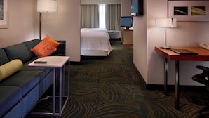 A hotel room with a bed, a desk, a chair, a sofa, a TV, and a lamp. - Springhill Suites by Marriott Mystic Waterford (Quaker Hill)