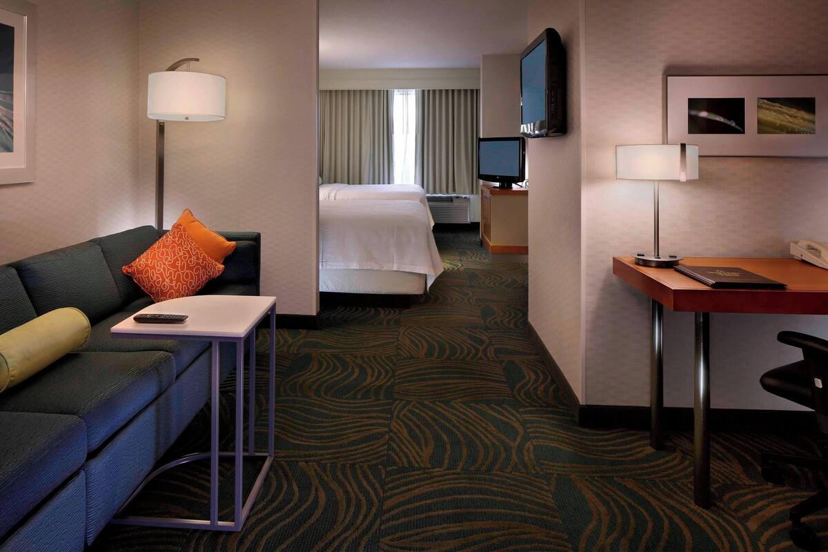 Une chambre d’hôtel équipée d’un lit, d’un bureau, d’une chaise, d’un canapé, d’une télévision et d’une lampe.