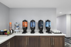 A hotel room with a coffee station featuring four dispensers labeled Regular Coffee, Robust Coffee, Decaf Coffee, and Hot Water.