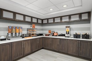 A modern kitchen with a breakfast bar, self-serve stations, and a coffee machine. - Homewood Suites by Hilton Williamsburg (Williamsburg)