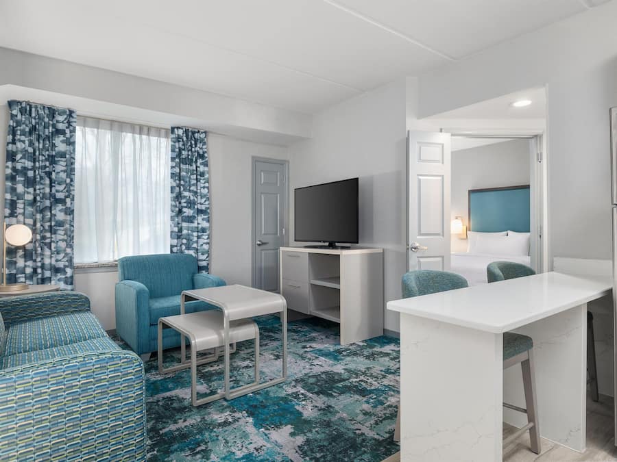 A compact living space with a sofa, a small TV, a desk, and a bed with a headboard.