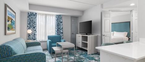 Een kleine hotelkamer met een bank, een tafeltje, een televisie, een bed en een bureau.