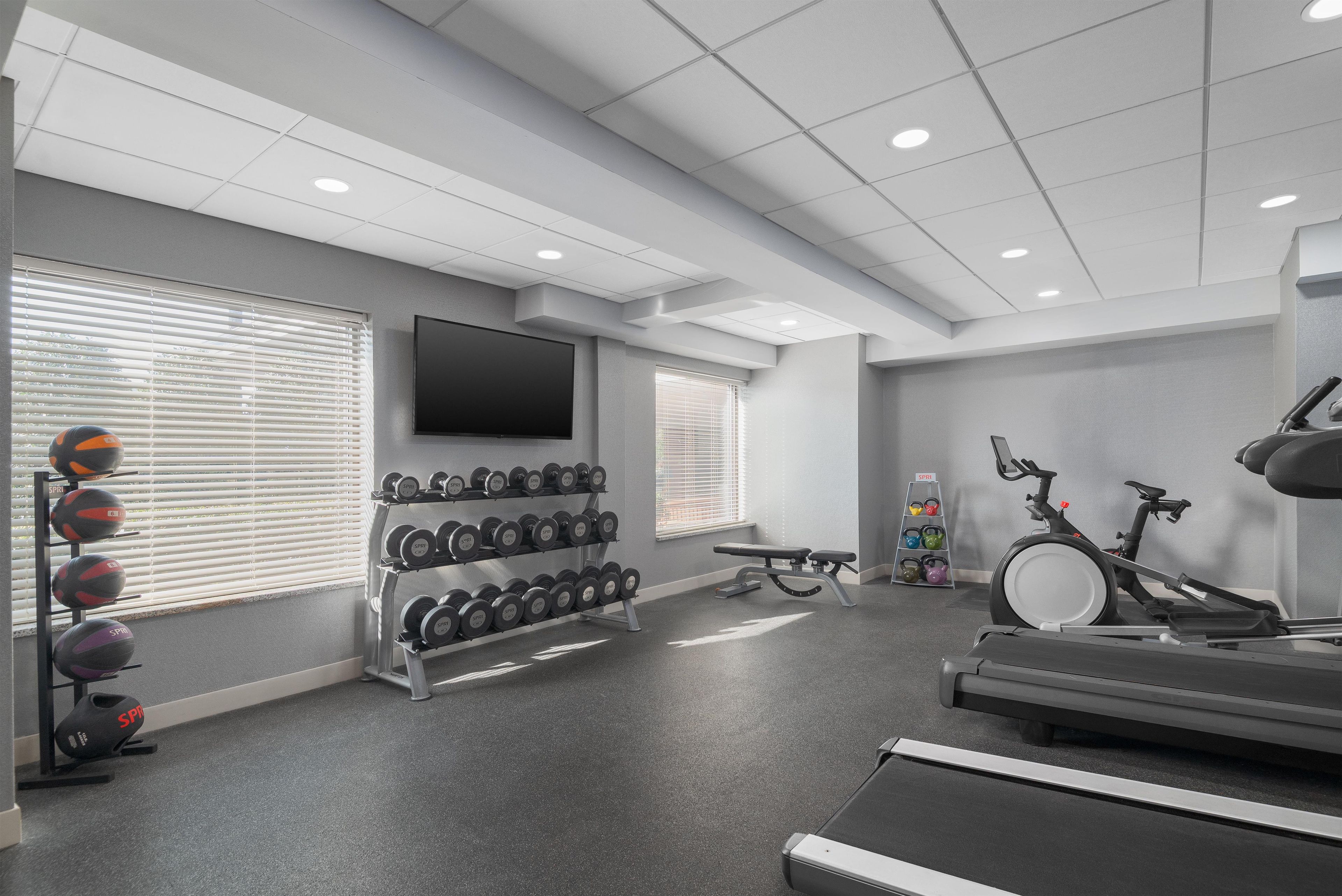 Een sportschool met trainingsapparatuur, een televisie en een bank.