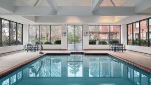 Ein Swimmingpool mit klaren Glasswänden, großen Fenstern und Ausblick ins Freie.