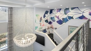 Ein modernes Interieur mit einer Treppe, einer Chandelüster und einer Wand mit abstrakter Kunst.