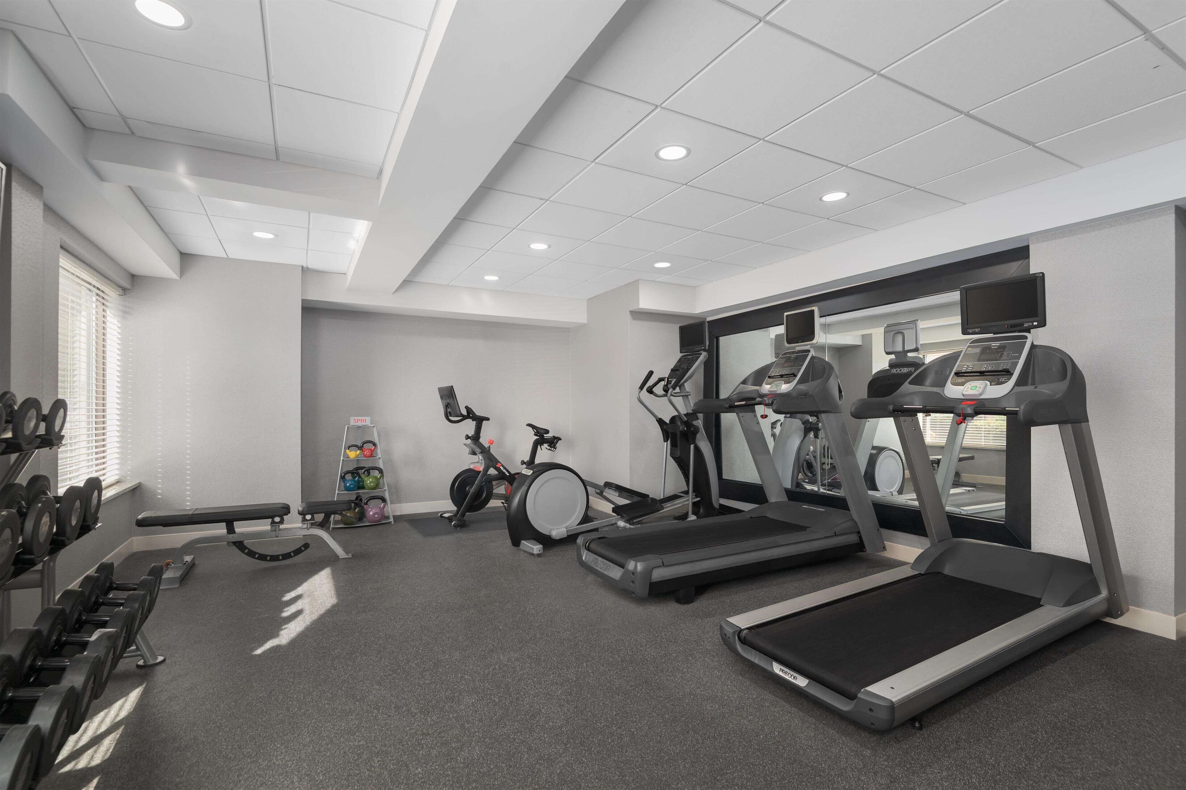 Un gimnasio con cintas de correr, bicicletas estáticas y equipo de levantamiento de pesas.
