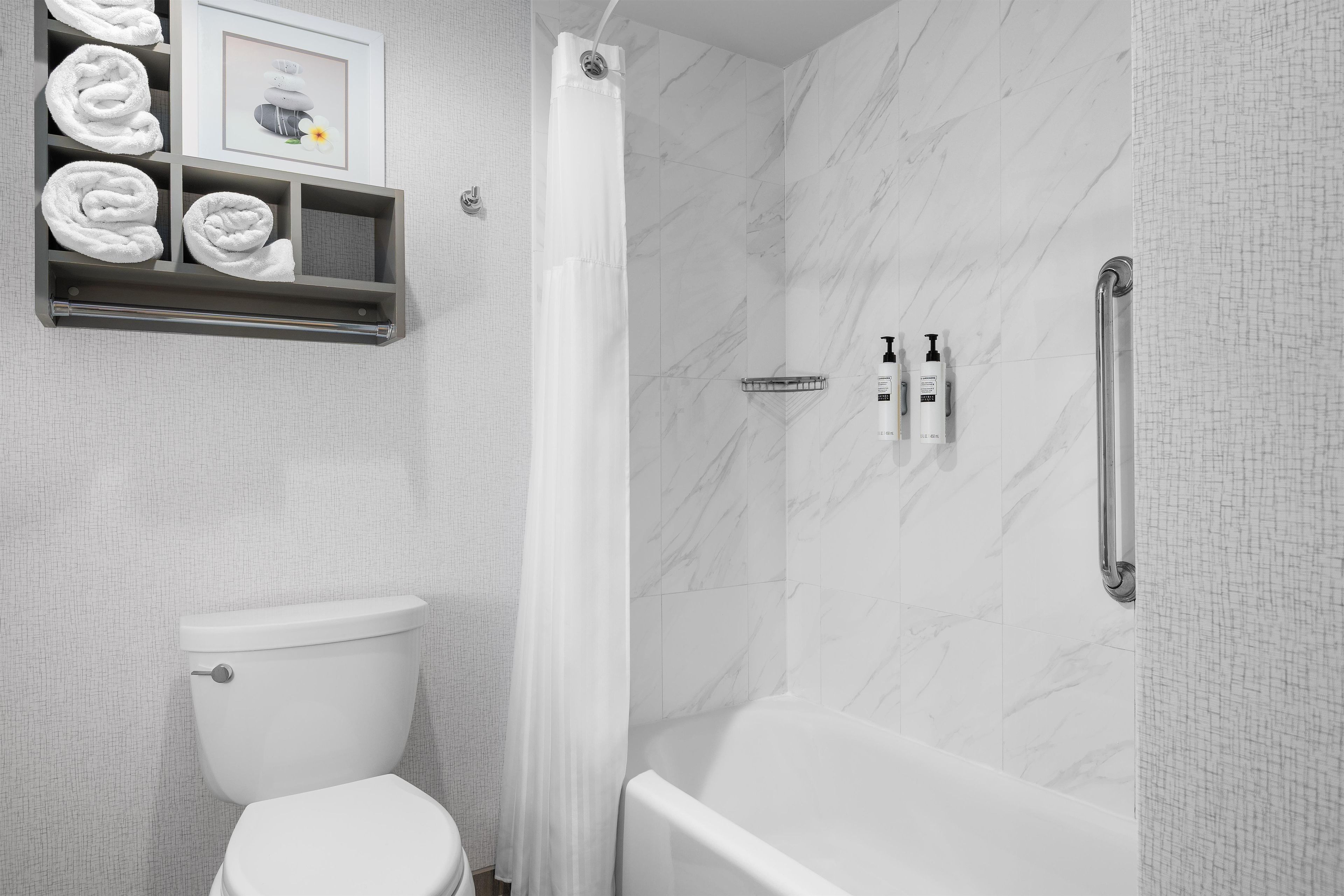 Een badkamer met een toilet, een douche met een glazen deur en een plank met handdoeken.
