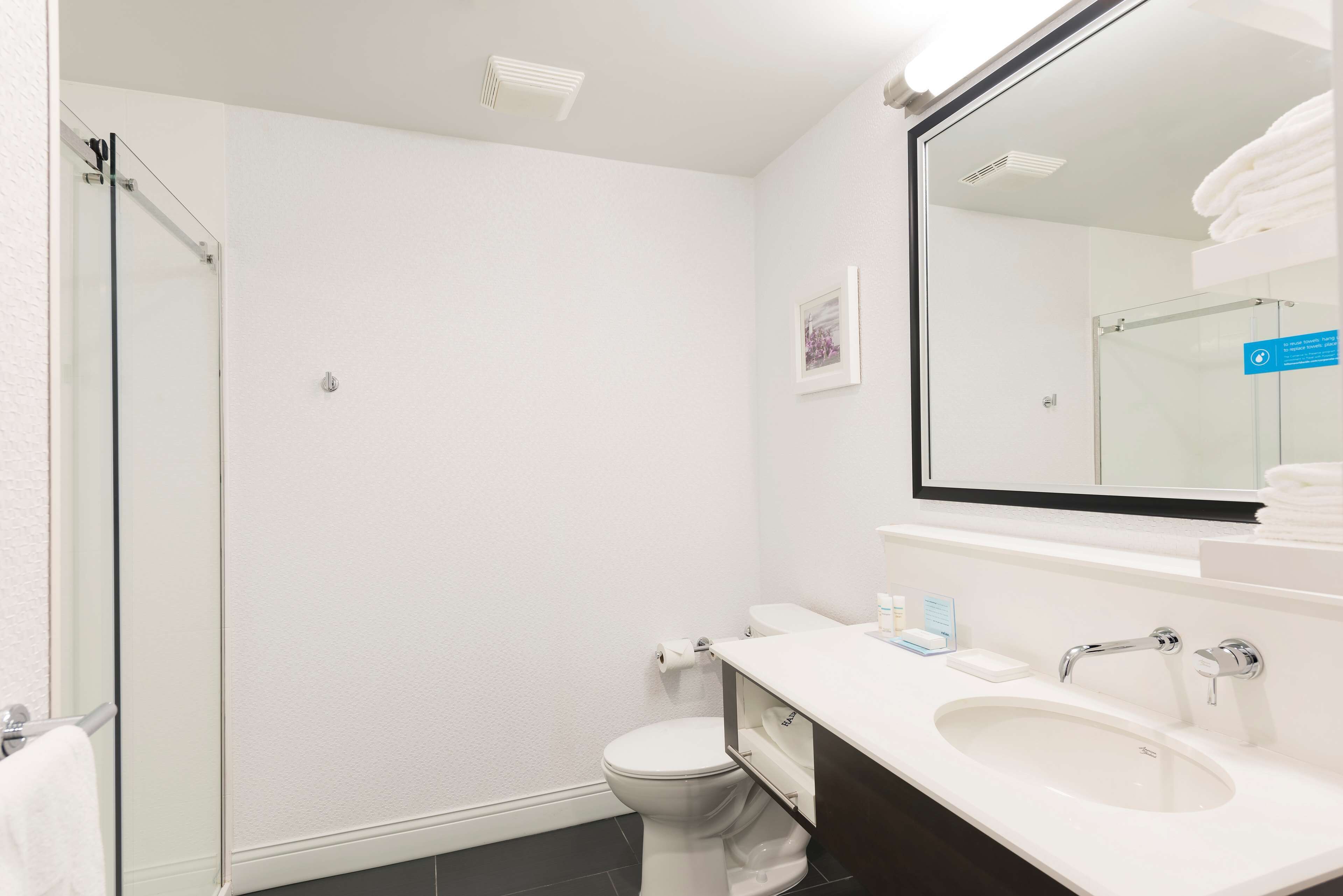 Een moderne badkamer met een douchecabine van glas, een wit toilet en een wastafel met een wastafel en spiegel.