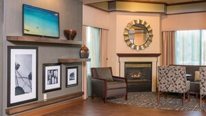 A modern living room with a fireplace, comfortable seating, and artwork on the walls. - Hampton Inn Midland (Midland)