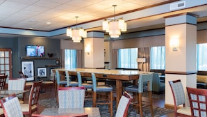 A hotel lobby with a bar area, seating arrangements, and a television screen. - Hampton Inn Midland (Midland)