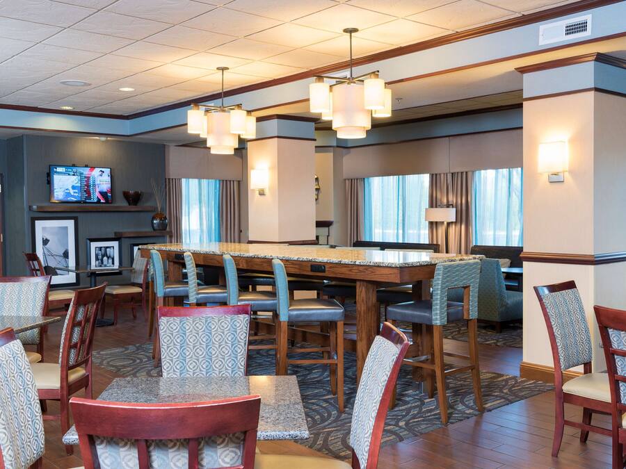 A hotel lobby with a bar area, seating arrangements, and a television screen.