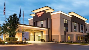 A modern Hampton Inn hotel with a well-lit entrance, American flags, and a clear sky. - Hampton Inn Midland (Midland)