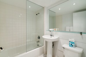 Un baño moderno con cabina de ducha de vidrio, lavamanos pedestal y retrete.