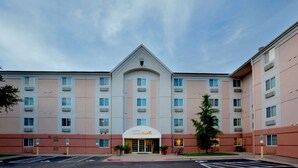 Et hotel med central indgang, flere etager og en parkeringsplads.