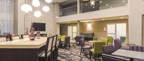 Un hall de hotel con comedor, asientos y un televisor.