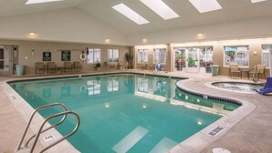 Une grande piscine intérieure à l’eau claire, entourée de chaises longues et dotée d’un toit ouvrant.