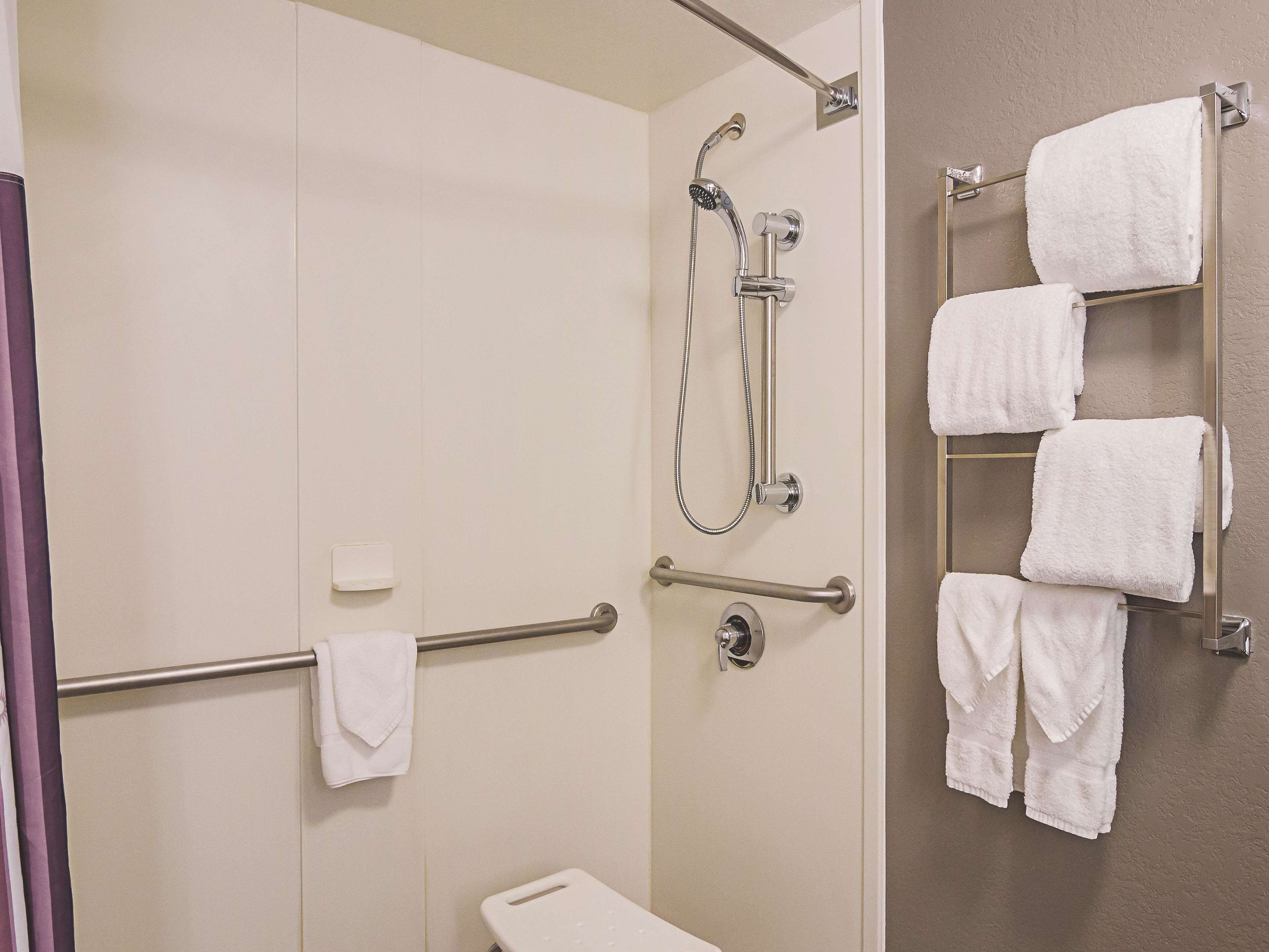 A bathroom with a shower, a toilet, and a towel rack with multiple towels.