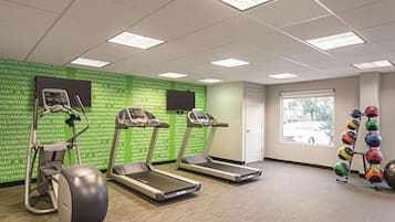 A fitness room with treadmills, an elliptical, and a set of exercise balls.