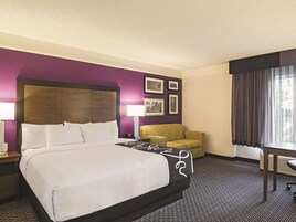 Een hotelkamer met een groot bed, een kleine bank, een bureau en een raam met gordijnen.