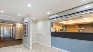 A hotel reception area with a reception desk, framed pictures on the wall, and a tiled floor.