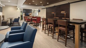 A modern hotel lobby with a bar area, seating arrangements, and a coffee station.