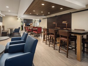 A modern hotel lobby with a bar area, seating arrangements, and a coffee station. - Holiday Inn Express Suites Belmont by IHG (Belmont)