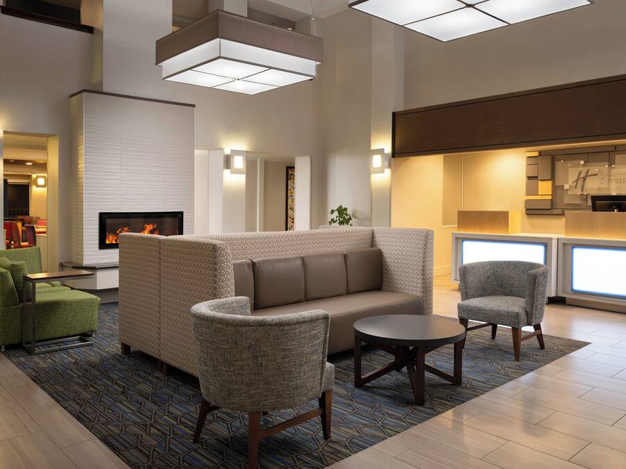 Un moderno hall de hotel con chimenea, zona de estar y mostrador de recepción.