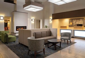 A modern hotel lobby with a fireplace, seating area, and a reception desk. - Holiday Inn Express Suites Belmont by IHG (Belmont)